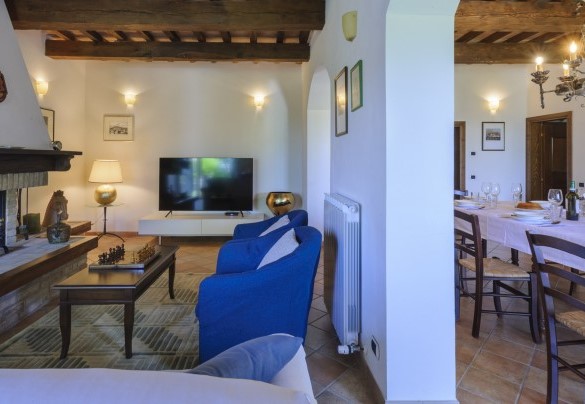 Ampia taverna composta da una zona pranzo, un salone con camino e zona tv, entrambe con accesso diretto al giardino tramite due porte finestra – Villa Banci