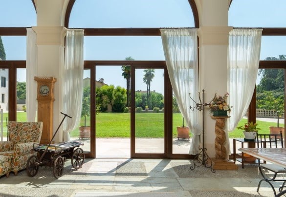 L’ampio porticato d’ingresso chiuso con ampie portefinestre è un vero e proprio giardino d’inverno che fa da perfetta liaison tra le aree esterne e le zone giorno interne – Villa Barchessa Panigai