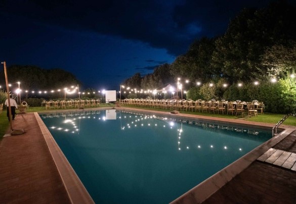 La piscina illuminata di sera allestita con luci decorative per eventi - Villa Borgo San Pietro 