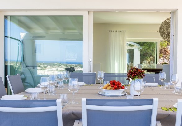 On the top floor, outside the living area, is the covered outdoor dining area furnished with a large table and sitting area; from here a few steps lead to the solarium and the panoramic swimming pool – Villa Calypso