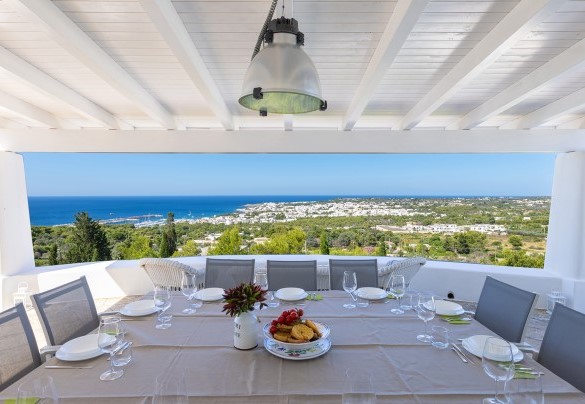 On the top floor, outside the living area, is the covered outdoor dining area furnished with a large table and sitting area; from here a few steps lead to the solarium and the panoramic swimming pool – Villa Calypso