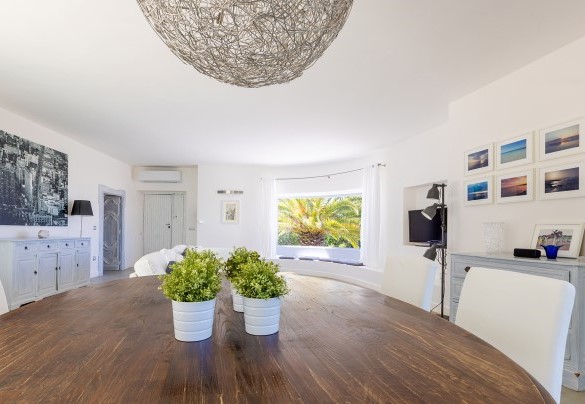 Large living area furnished with a spectacular dining table and sofas placed in front of large windows that frame the boundless panorama - Villa Calypso