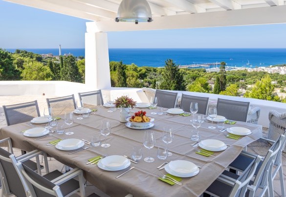On the top floor, outside the living area, is the covered outdoor dining area furnished with a large table and sitting area; from here a few steps lead to the solarium and the panoramic swimming pool – Villa Calypso