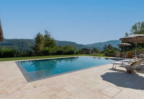 La splendida piscina con solarium in travertino, arredato con lettini e ombrelloni - Villa Carlotta