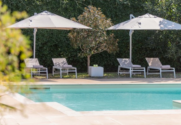 Lungo il perimetro piastrellato della piscina sono posizionati lettini ed ombrelloni - Villa Kimia