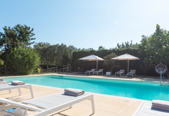 Lungo il perimetro piastrellato della piscina sono posizionati lettini ed ombrelloni - Villa Kimia