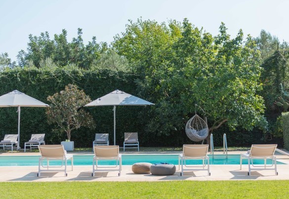Lungo il perimetro piastrellato della piscina sono posizionati lettini ed ombrelloni - Villa Kimia