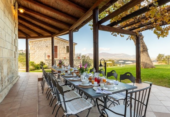Il porticato ospita un tavolo con sedie per pranzi all'aperto - Villa Cusano 