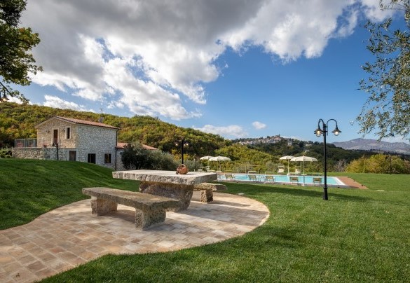 Seduta in pietra con la piscina e l'annesso sullo sfondo - Villa Cusano