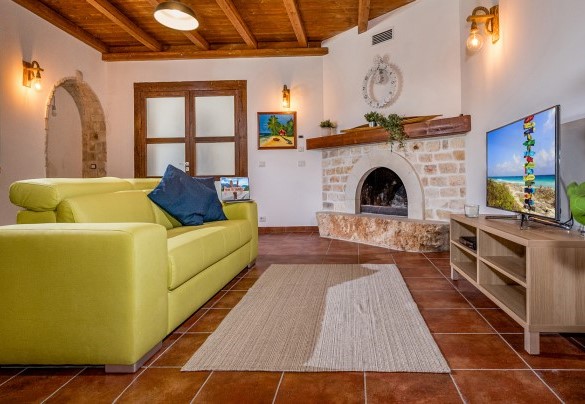 Area con divano completata da tv e camino funzionante - Villa Cutrera