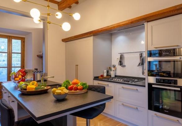 La cucina con elettrodomestici Miele e Bosch, piano in granito, isola centrale e con accesso alla terrazza dove è allestita la zona pranzo esterna - Villa De Cerchi
