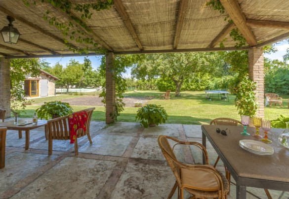 Covered outdoor area with wooden lounges and garden views - Villa Deda