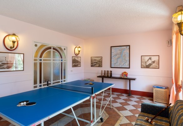 sala giochi attrezzata con un tavolo da ping pong, un divano e una varietà di giochi per bambini di tutte le età – Villa Alba del Lario