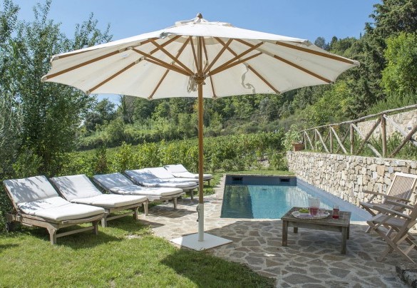The sunbathing area, in part paved up in stone around the pool and in part lawn, is provided with sunbeds and umbrellas and is bounded on one side by dry stone walls – Villa Delle Upupe 