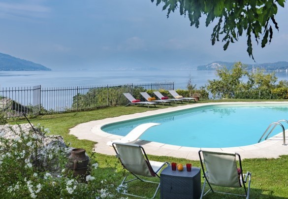 The irregularly shaped swimming pool is surrounded by a carpet of grass and a lush garden – Villa Eden