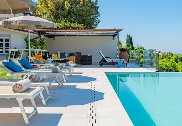 La piscina a sfioro adiagata su un solarium in travertino - Villa Elena