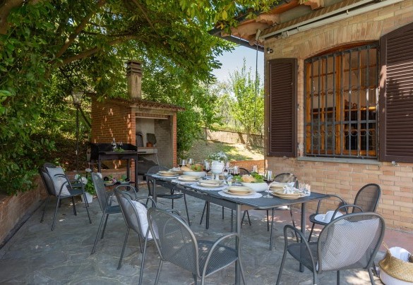 At the exit of the living room on the ground floor is a large terrace composed of a dining area, with barbecue and wood oven – Villa Fiorentini