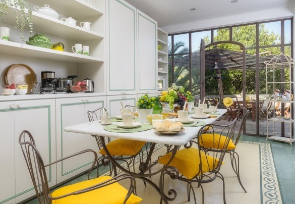 La bellissima veranda racchiusa da vetrate rifinite in ferro battuto e molto luminosa, dove è allestita la sala da pranzo con un elegante tavolo in marmo di fronte all’area pranzo esterna – Villa Gaius
