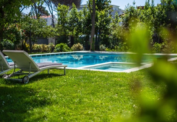 Nell’estesa superficie a prato che cinge la piscina sono presenti numerosi lettini prendisole e una doccia esterna – Villa Guidi