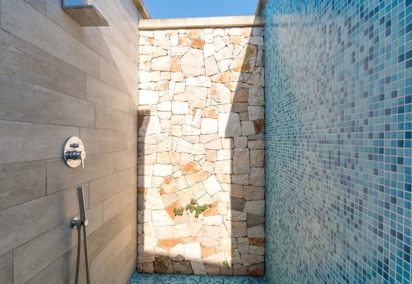 La pratica doccia a vista con muri in pietra viva è a servizio della piscina - Villa I Chiani