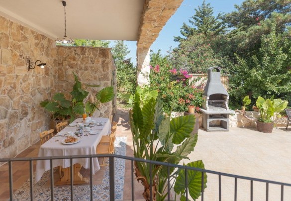 Zona esterna sotto la pergola con pietra a vista e barbecue – Villa I Mori
