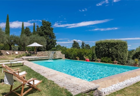 La vasca rettangolare e a sfioro su due lati, rivestita e bordata da pietra di travertino e dotata di gradini di accesso - Villa Il Cedro
