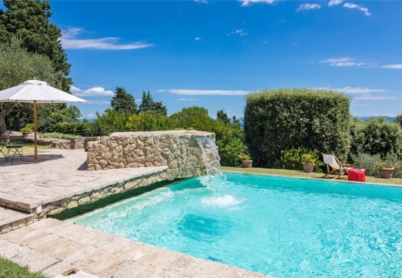 La vasca rettangolare e a sfioro su due lati, rivestita e bordata da pietra di travertino e dotata di gradini di accesso - Villa Il Cedro