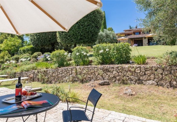 Attorno alla piscina, munita di faretti interni, nell’area prendisole delimitata da uno schermo di siepi, sono disposti lettini, ombrelloni e tavolini - Villa Il Cedro