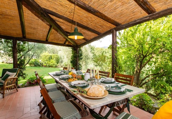 The portico shades the elegant table prepared for outdoor dining - Villa Il Colle di Moriano
