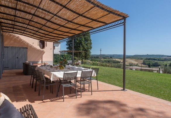 L’ampio pergolato lastricato, arredato con tavolo da pranzo e zona salotto – Villa Il Pino