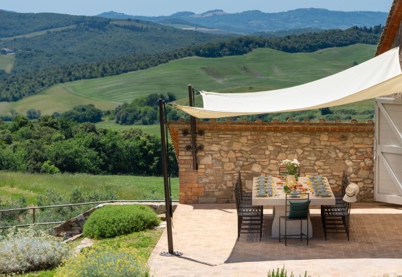 L’area pranzo esterna è allestita sulla pavimentazione in cotto di fronte alla cucina - Villa Il Pozzo