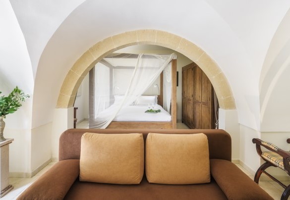 Un arco in pietra separa il salottino dal letto a baldacchino nella camera matrimoniale padronale - Villa La Dolce Vita