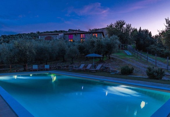 The lit up swimming pool and the farmhouse in the glow of the sunset – Villa La Poiana 10