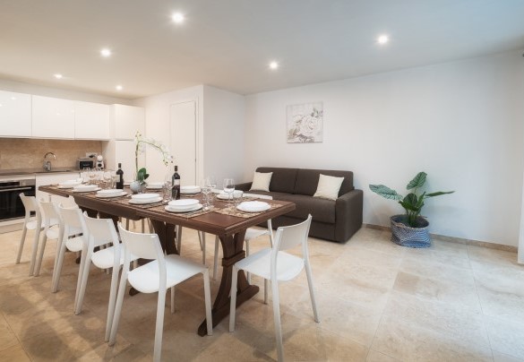 Ampia zona soggiorno open space con cucina a vista, tavolo da pranzo e divano al piano sottostrada– Villa Laconella