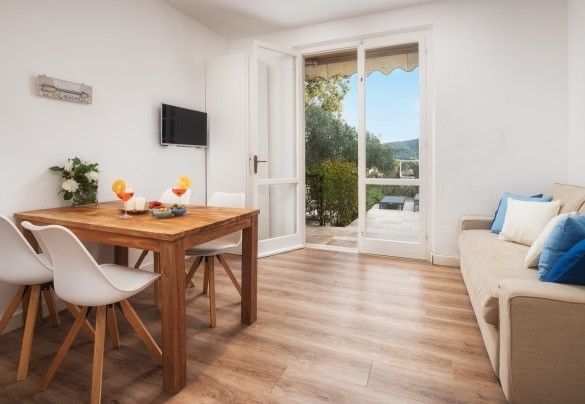Zona giorno n. 3 al piano terra con tavolo, divano e TV – Villa Laconella