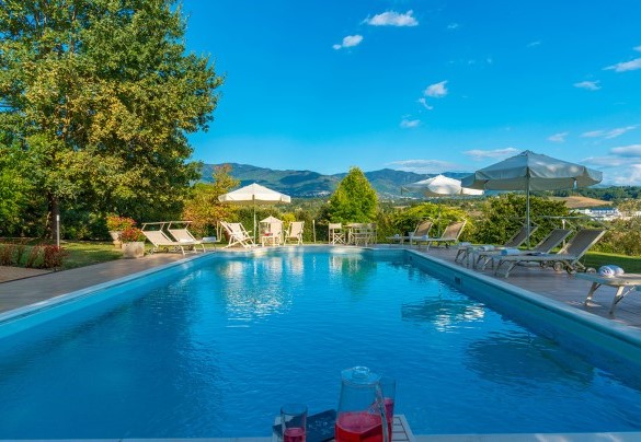 Il solarium attrezzato con lettini, sdraio, ombrelloni e tavolini, al centro del quale è adagiata la piscina – Villa Leonardo