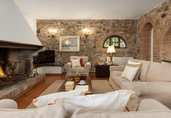 The open-plan living room, with fireplace and TV, and dining room in the main house – Villa Loredana