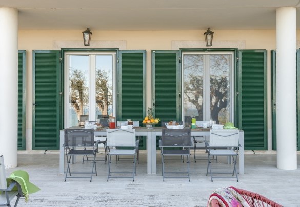Portico attrezzato con tavolo e sedie, adiacente alla cucina e sala da pranzo – Villa Lucente