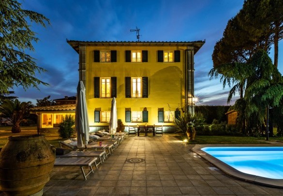 The pool with the solarium area with sunbeds and umbrellas illuminated at sunset – Villa Luigina