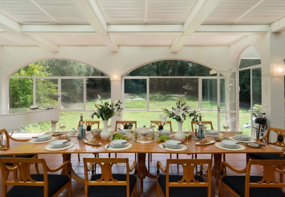 The large veranda set up with living and dining areas, grand piano and study corner, with access to the garden via a French window and then down a few steps complete with banister - Villa Manganelli