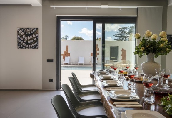 The dining table in the open-plan living connected by French windows to the pool area - Villa Maria Paradiso