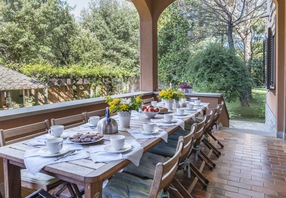 Sotto un porticato ampio, all’uscita della sala da pranzo, si trova l’area allestita per mangiare all’aperto - Villa Michelangelo