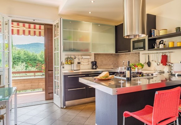 Cucina, con isola centrale e tv satellitare, con accesso diretto alla zona pranzo esterna al piano terra – Villa Monica