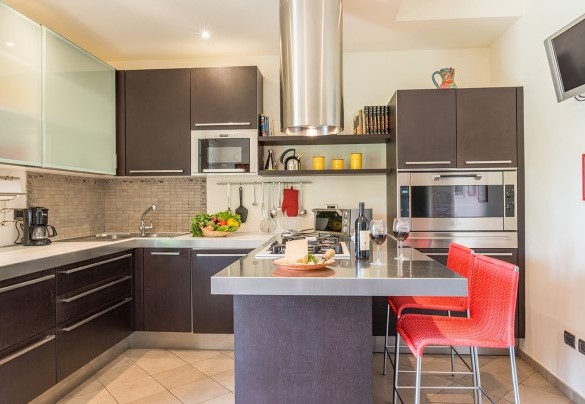 Cucina, con isola centrale e tv satellitare, con accesso diretto alla zona pranzo esterna al piano terra – Villa Monica