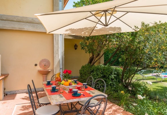 La zona per mangiare all’aperto con ombrellone, tavolo e barbecue in muratura – Villa Monica