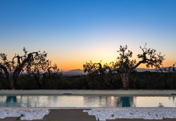 La piscina con area solarium illuminata al tramonto – Villa Monnalisa