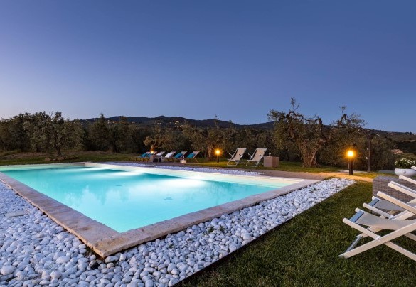La piscina con area solarium illuminata al tramonto – Villa Monnalisa