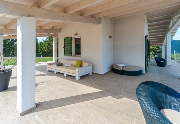 Back porch with wooden ceiling and contemporary style seating, overlooking the green hills and entrance to the first floor rooms - Dimora Montefalcone