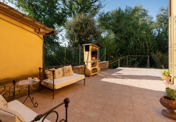 Di fronte alla cucina è allestita una zona living esterna con barbecue in muratura – Villa Montefalconi