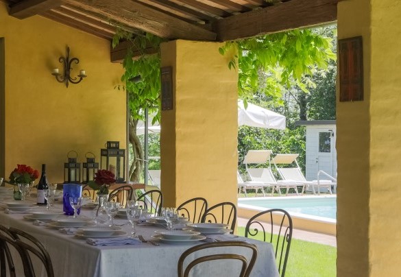 Il punto di forza è costituito dal grande portico con vista sul giardino e sulla piscina, arredato con tavolo e sedie per cene conviviali – Villa Mosca